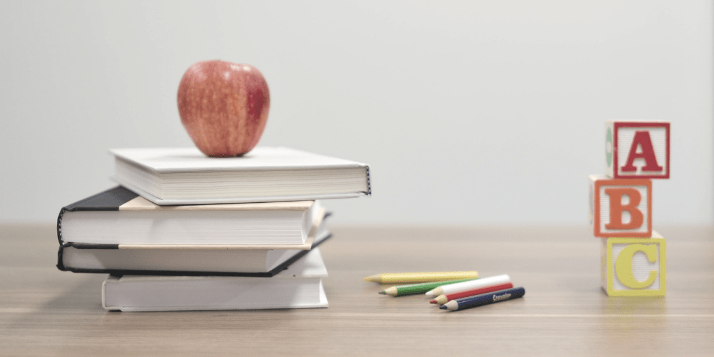 Chibimundo - educar antes educar ahora - mesa con libros una manzana y bloques de madera con letras